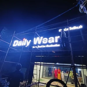 Backlit elevation name board for clothing store 'Daily Wear' installed at night