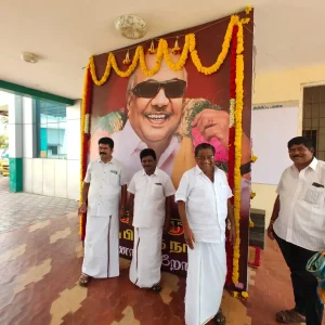 Local leaders in traditional attire pose in front of a mural featuring [Name of Figure], decorated with floral garlands.