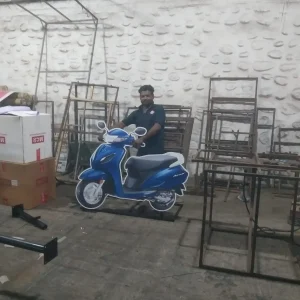 Man posing with a cardboard cutout of a blue scooter for promotional purposes