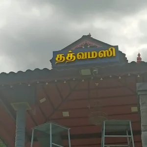 Illuminated name board at the entrance of a temple with Tamil text